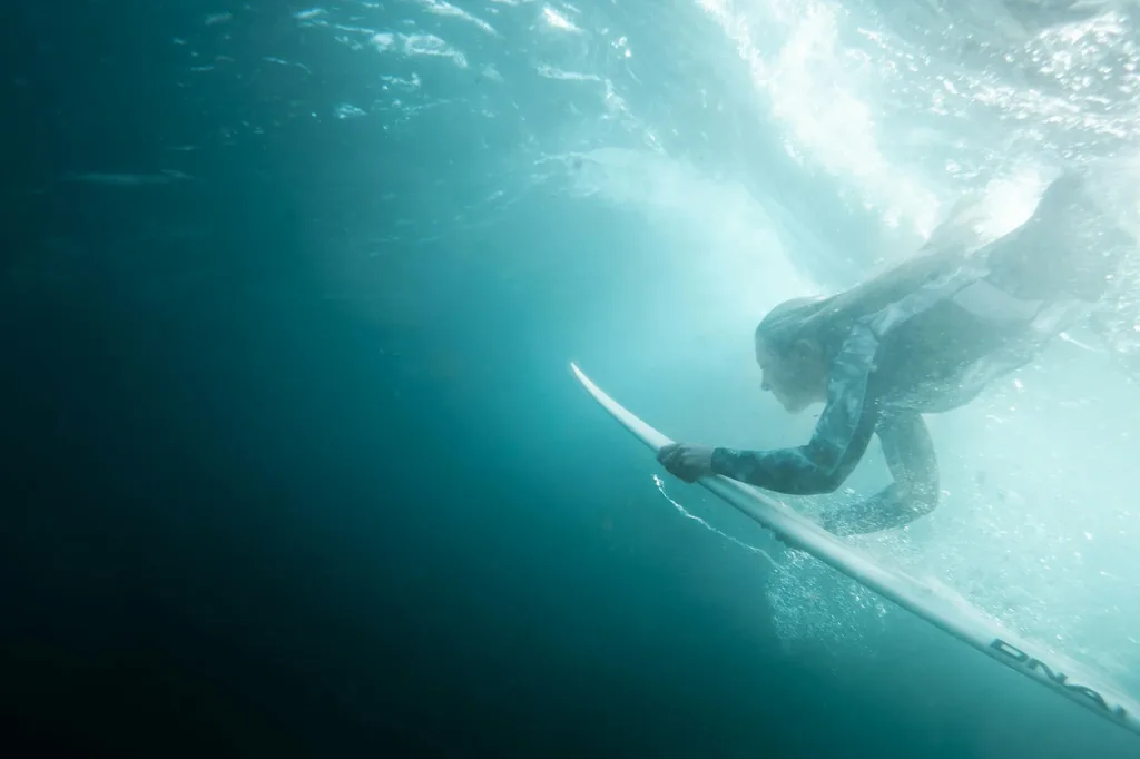 Underwater view of a surfer pushing a board under a wave