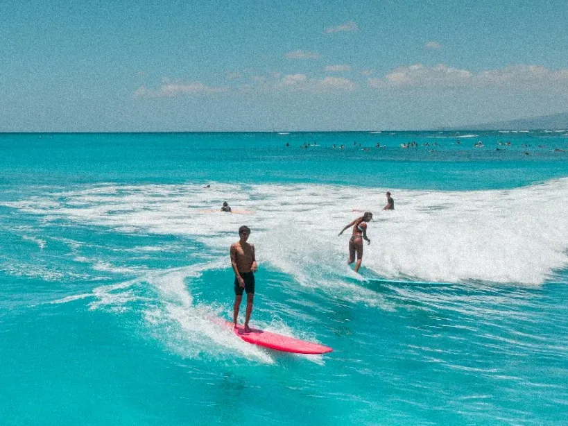 Two surfers riding a small wave in bright turquoise water