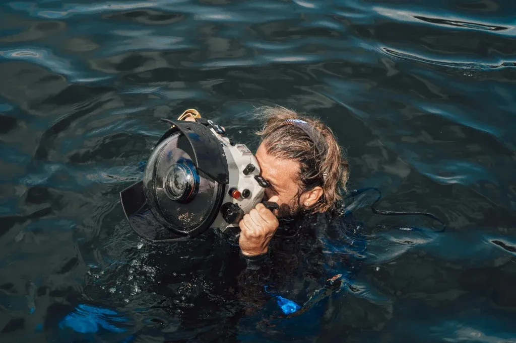Water photographer holding a camera in a dome-port housing at the surface