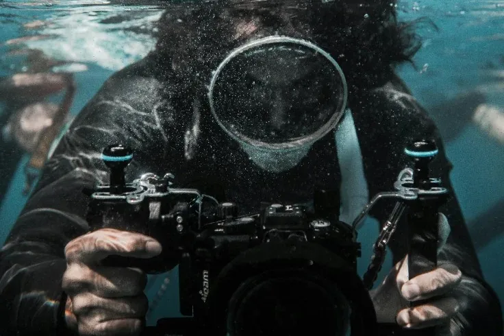 Underwater photographer holding a camera in a water housing