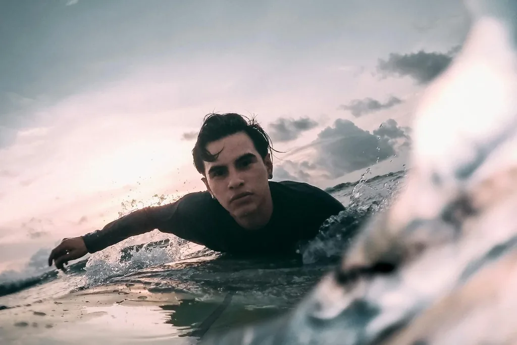 Surfer paddling in the water at dusk, shot from water level