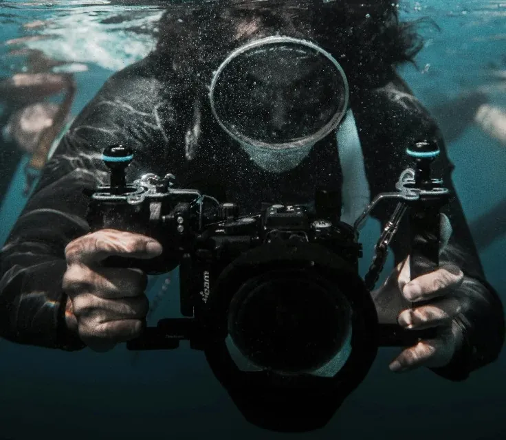 Underwater photographer holding a camera in a waterproof housing