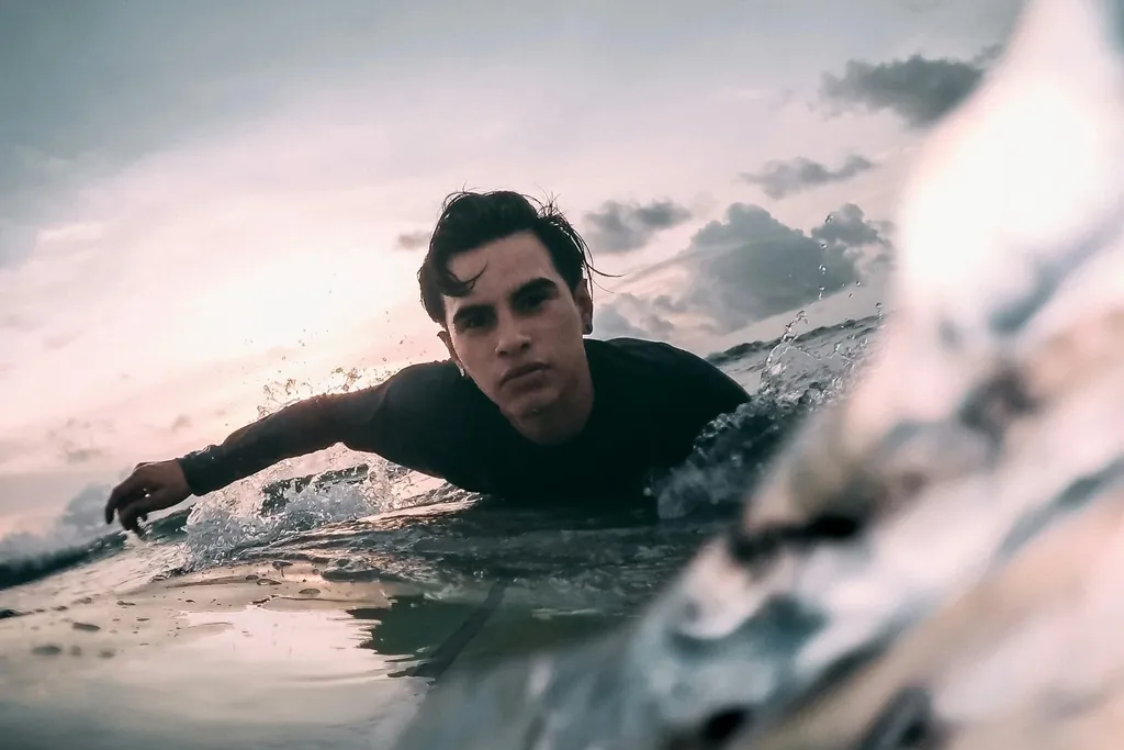 Surfer paddling toward the camera at water level, face focused